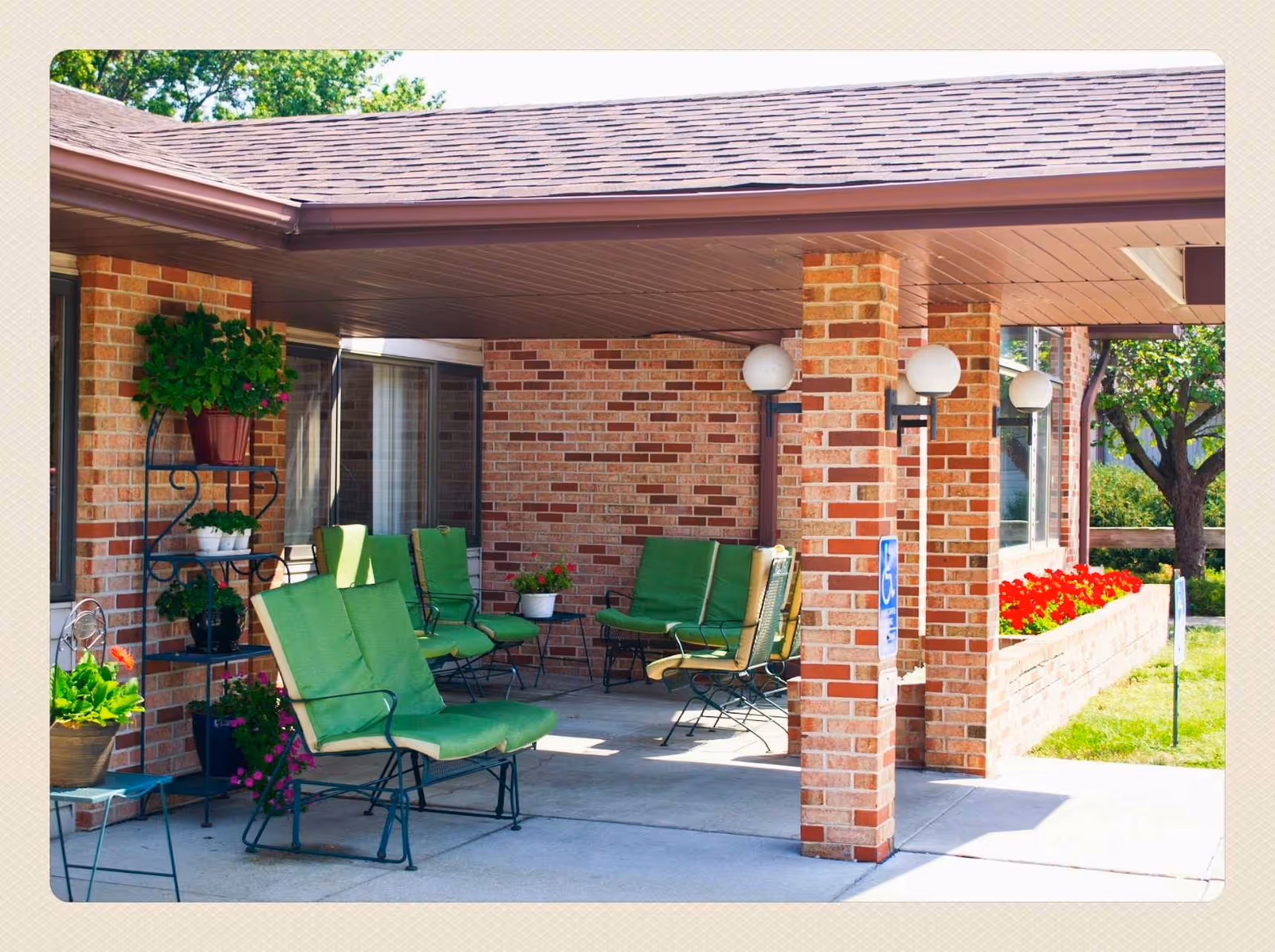 Outdoor brick patio at Evergreen Estates I with green cushioned chairs and planters.