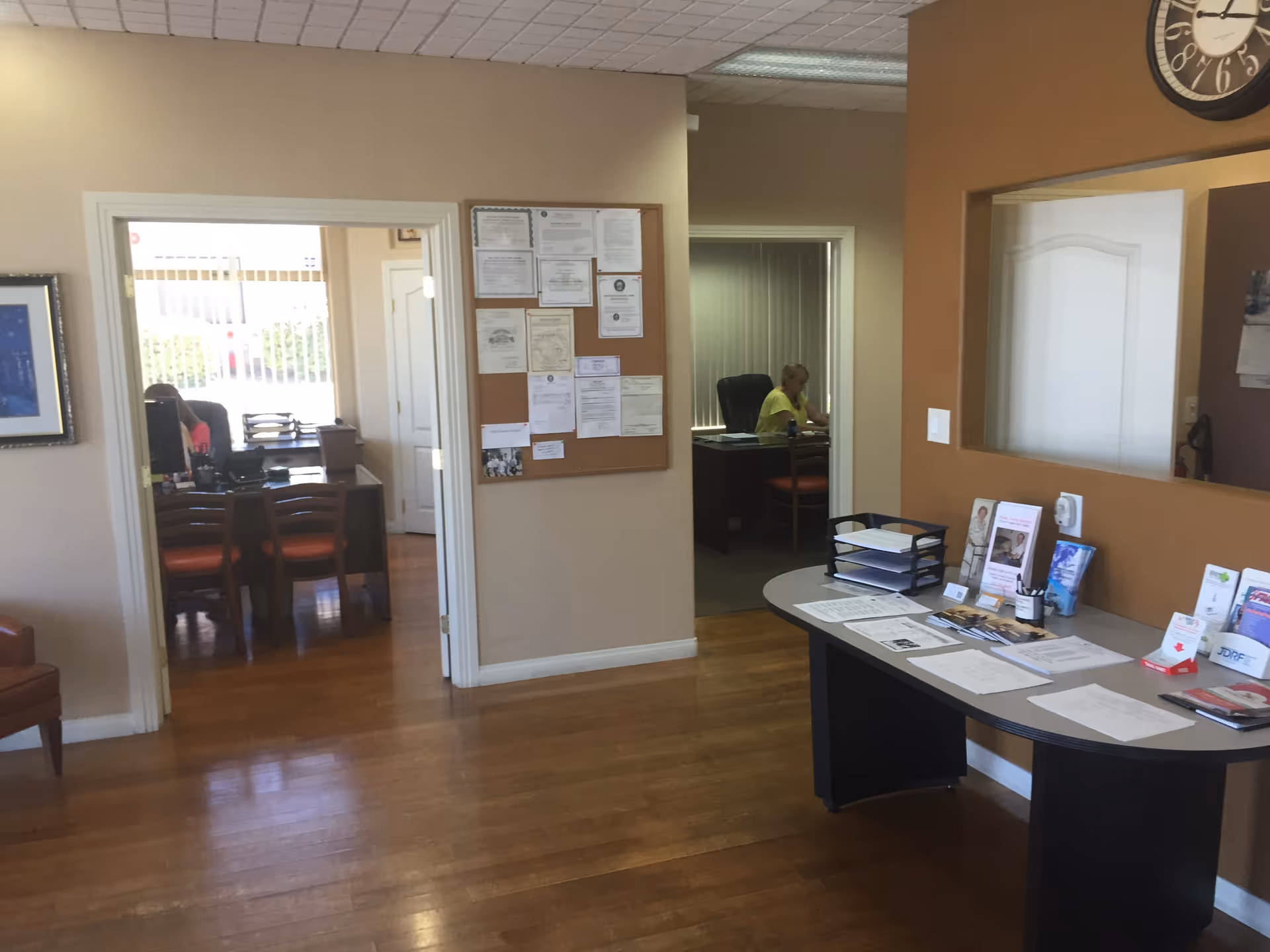 Reception desk in a senior living facility lobby with bulletin board and corridor doors
