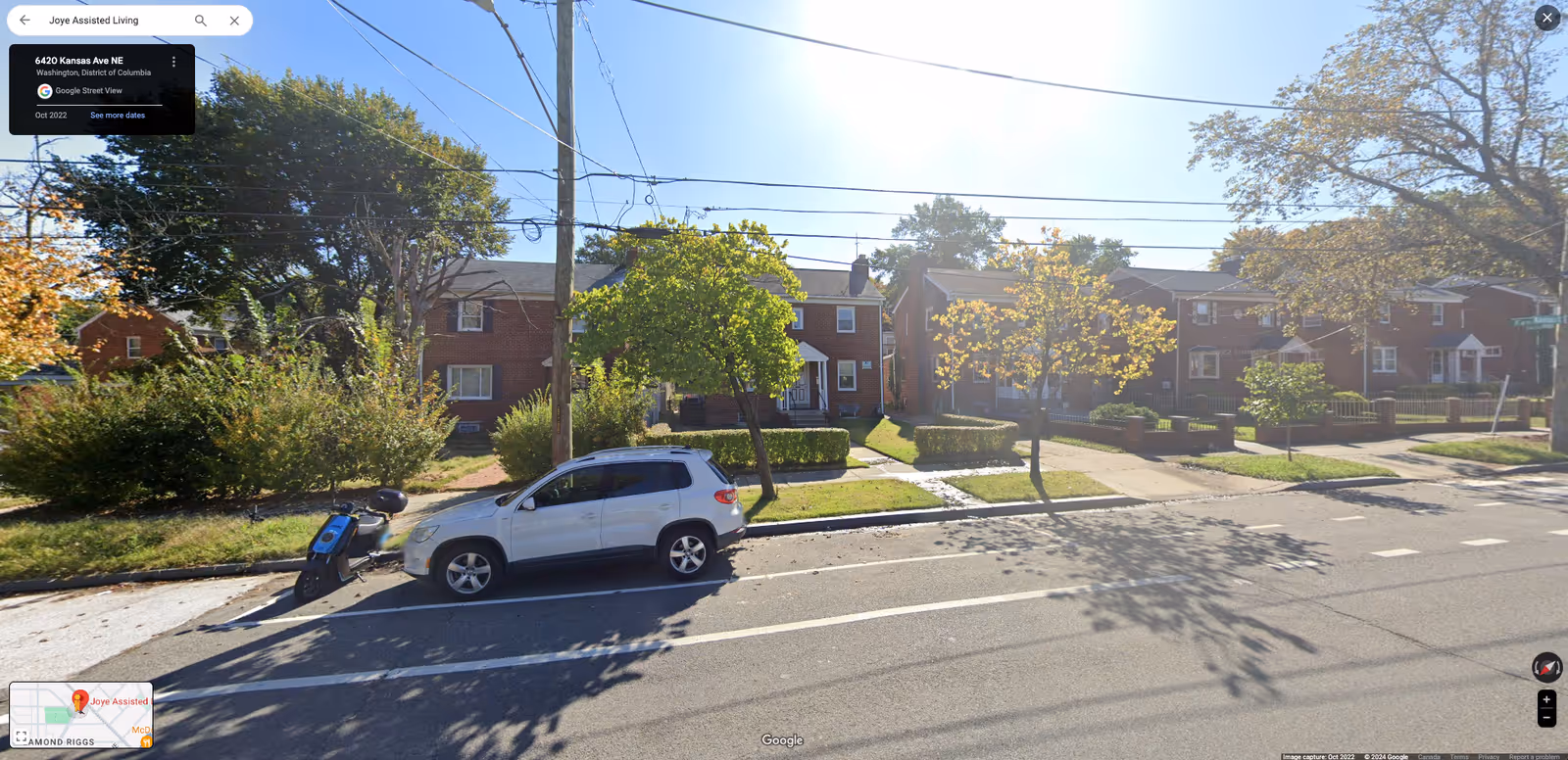 Street view of Joye Assisted Living exterior with brick buildings, trees, and parked vehicles.