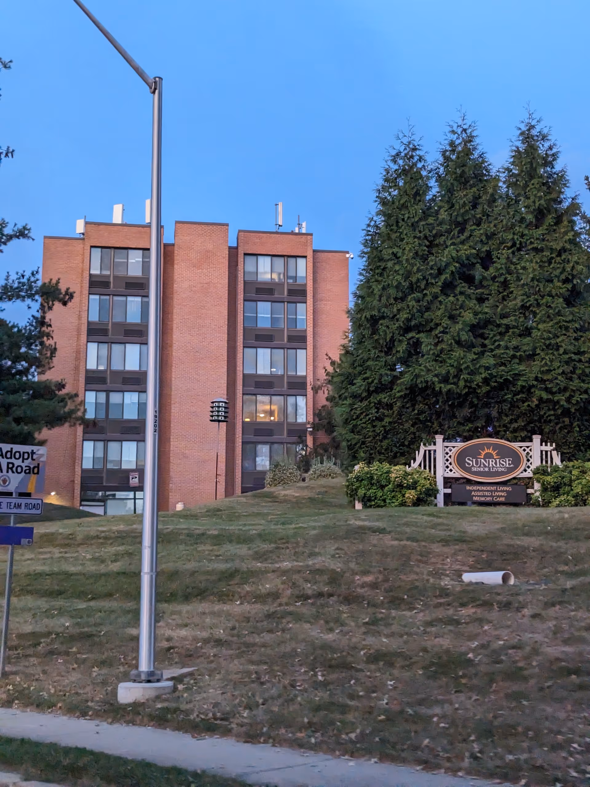 Front exterior view of Sunrise at Montgomery Village senior living building with sign and lawn.