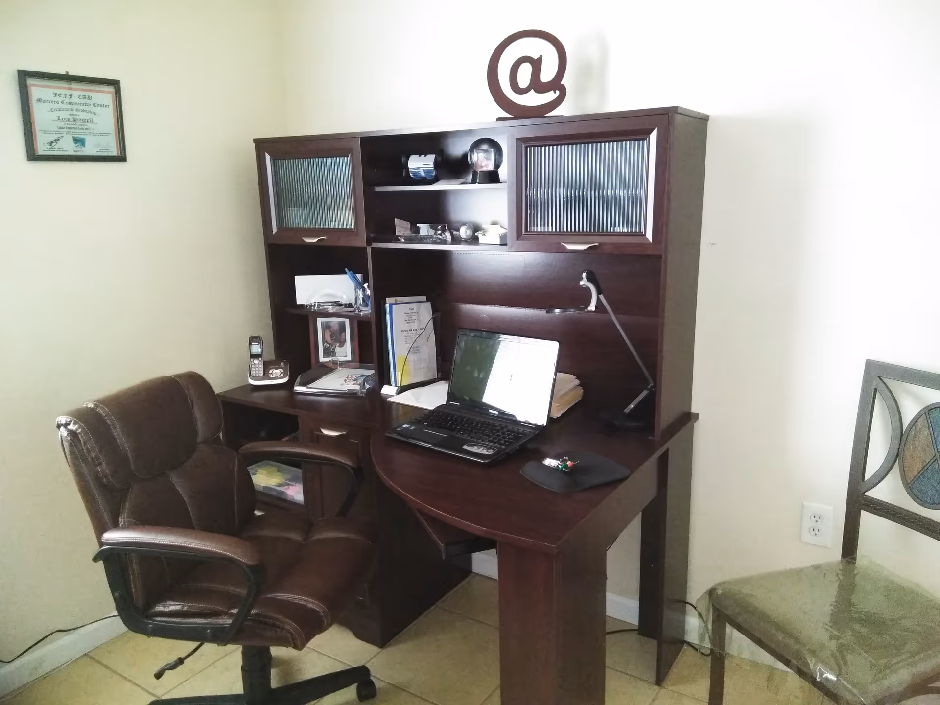 Dark wooden desk with laptop, chair, and shelves in a compact home office.