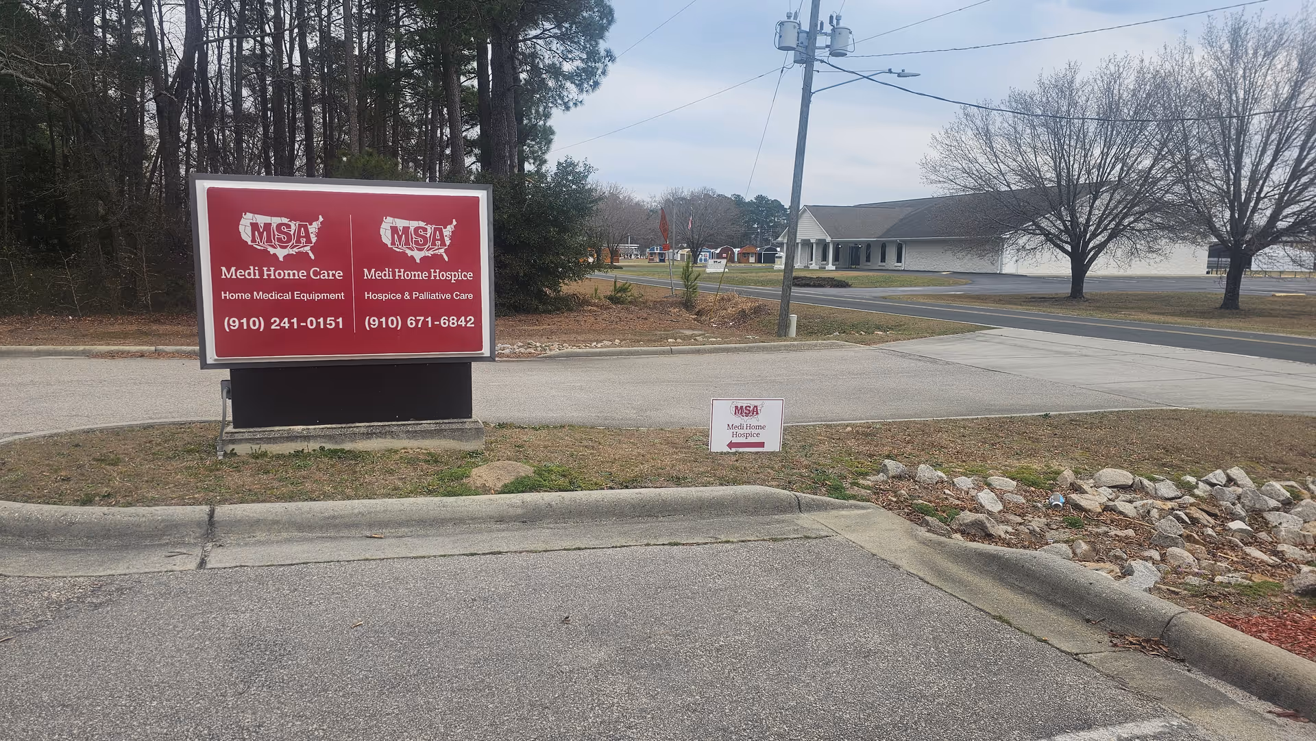A red Medi Home Care sign sits by the parking lot with a building in background.