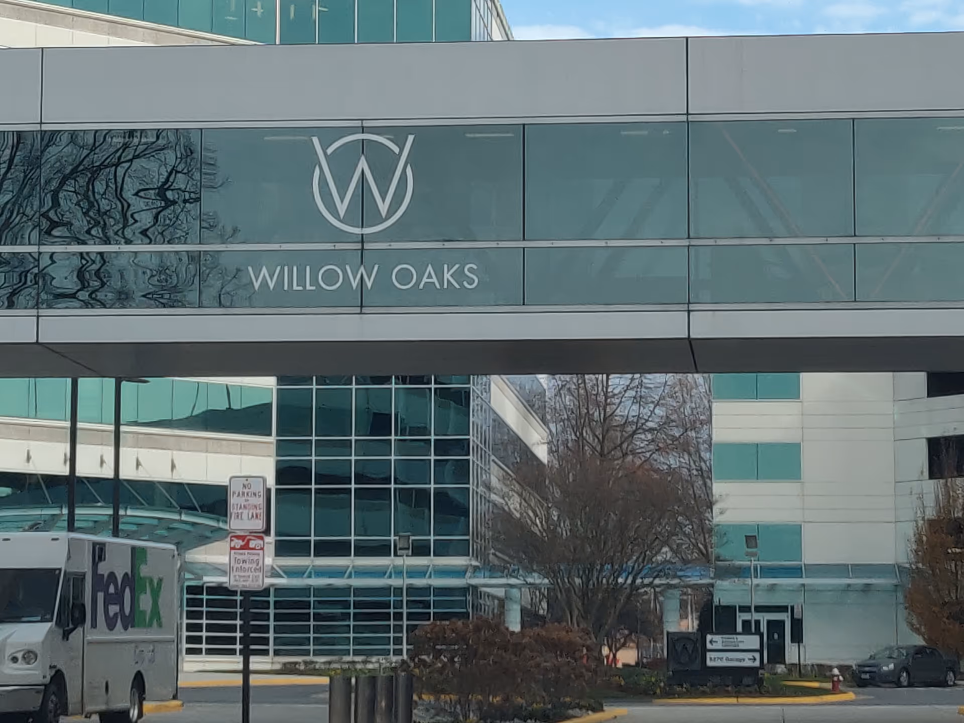 Exterior view of a modern medical facility with Willow Oaks signage and a pedestrian bridge.