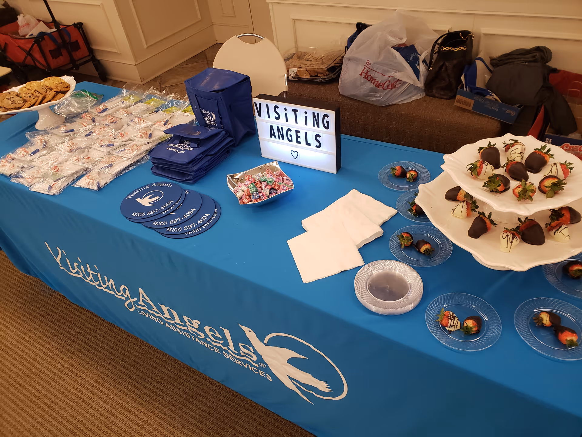 Indoor table with snacks and a Visiting Angels banner in a facility setting.