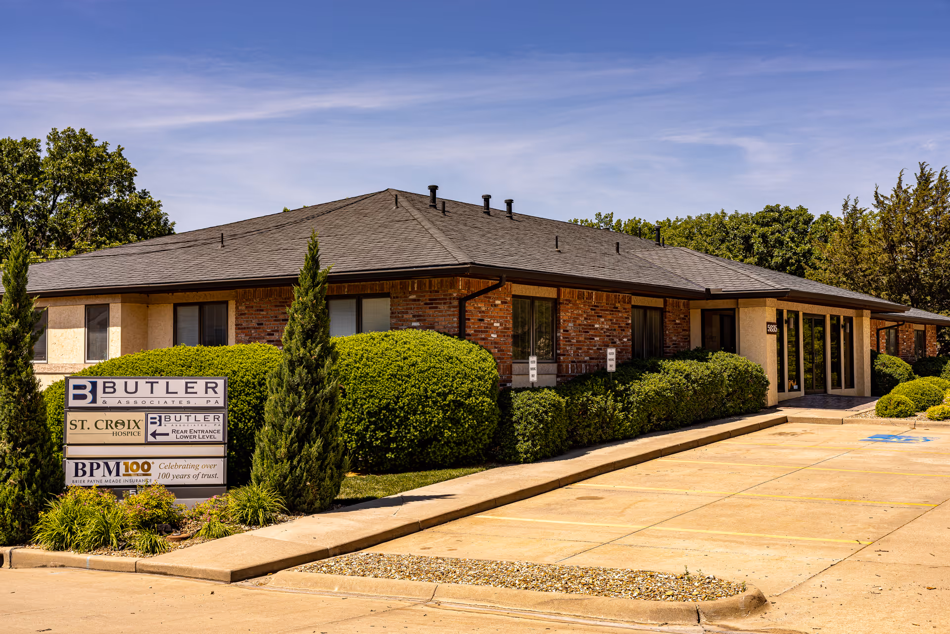Front view of a single-story brick building labeled St. Croix Hospice with shrubs.