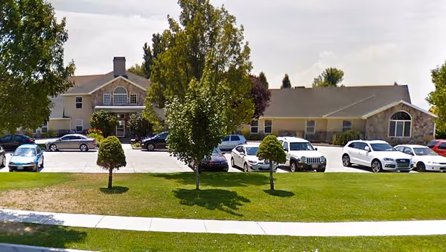 Exterior view of Bel Aire Senior Living with a front parking lot and trees.
