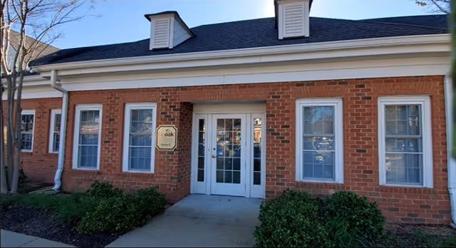 Exterior brick building entrance with white double doors and shrubs in front