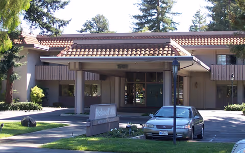 Senior living facility entrance with porte-cochere and parked car.