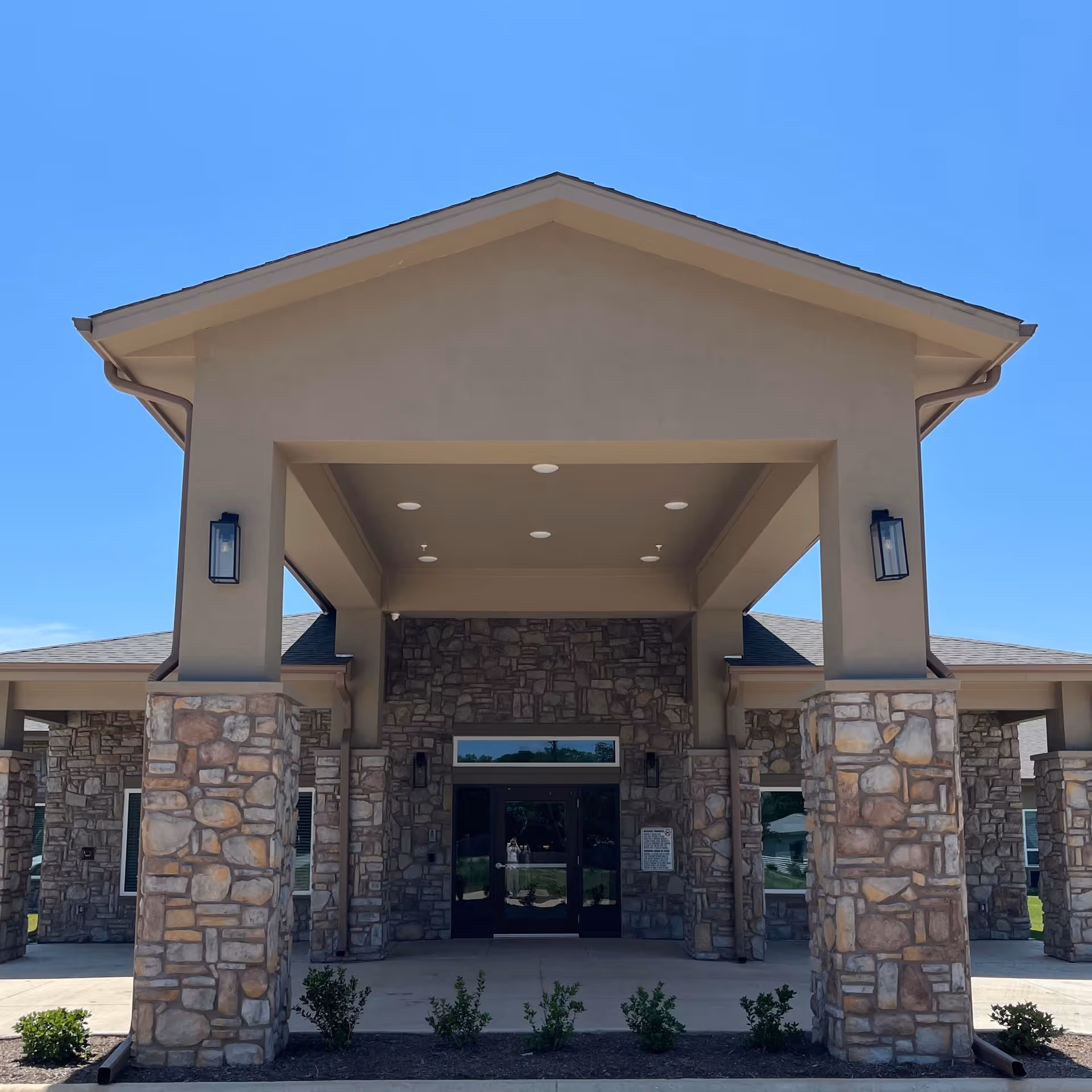 Exterior view of the care center entrance with stone pillars and a peaked roof.