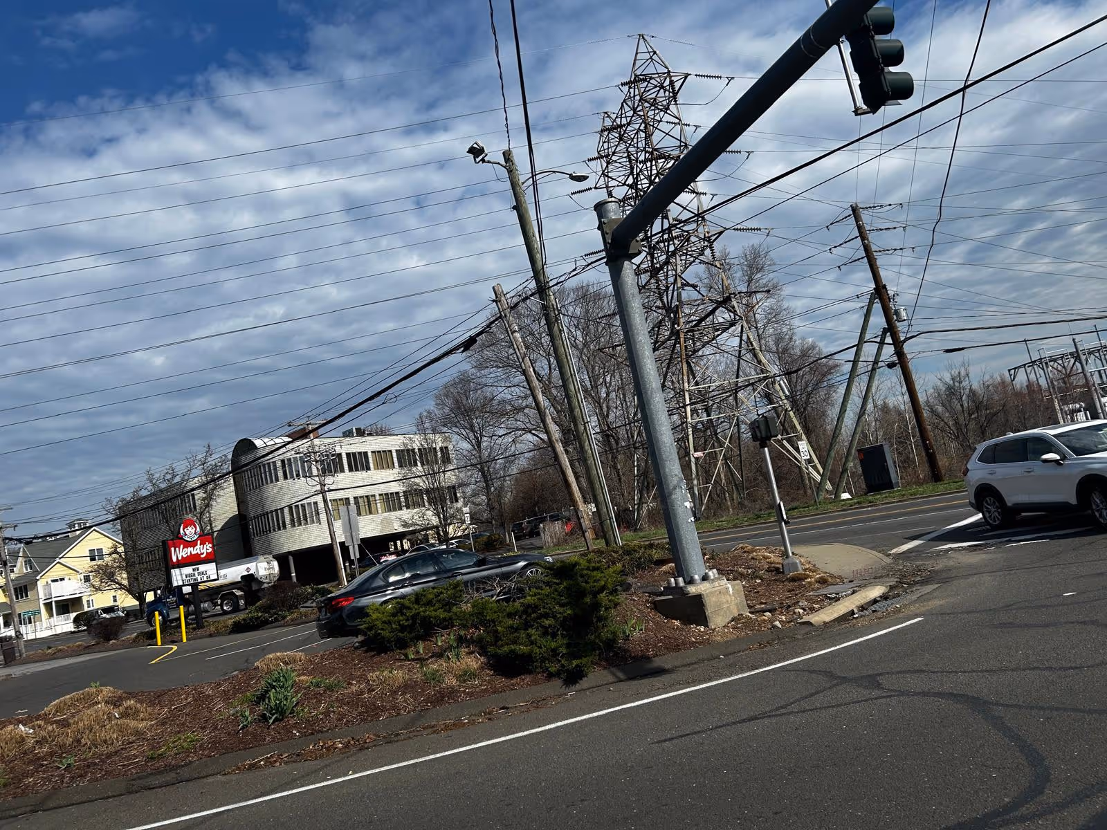 Urban street scene with power lines, a Wendy's restaurant, and parked cars.