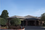 Front exterior of Arbors at Sylvania senior living facility with brick arches and landscaping