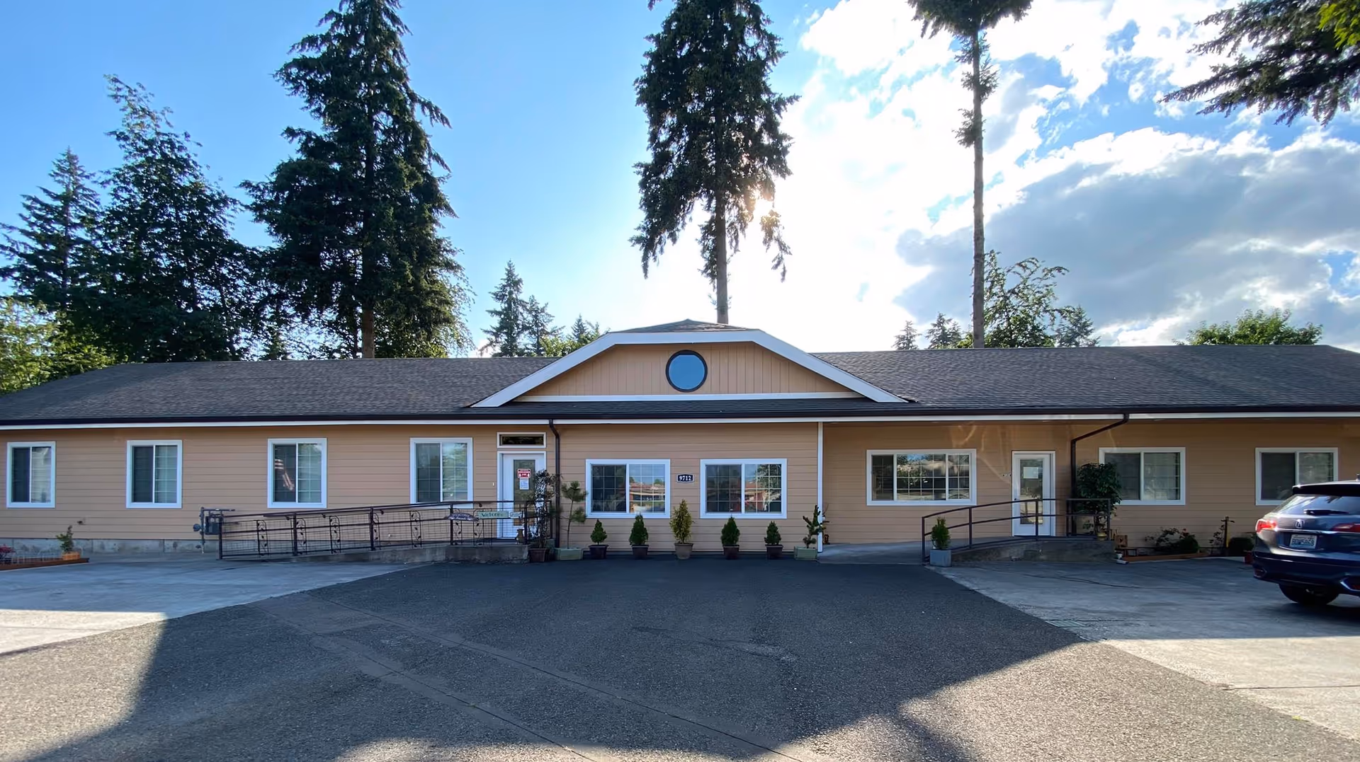 Single-story beige senior living facility with a central gable and parked car.