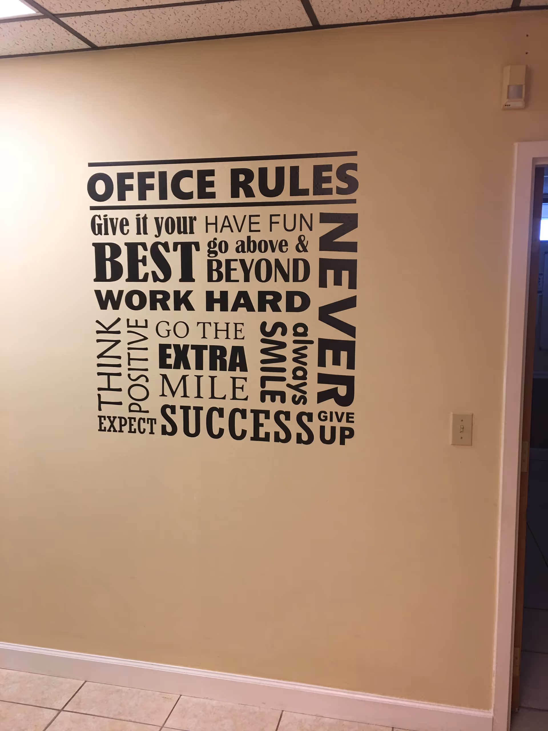 Beige interior hallway with a large 'OFFICE RULES' wall decal.