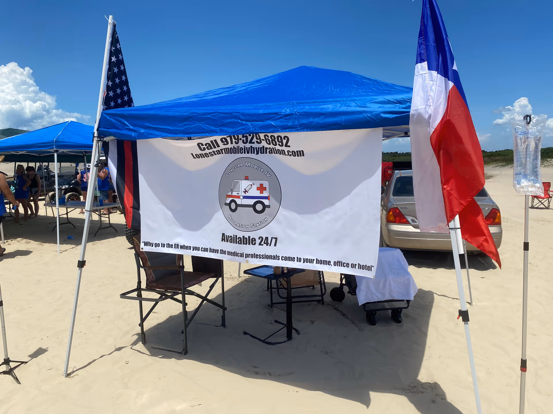 Blue canopy tent on a sandy beach with Lonestar Mobile IV Hydration banner and chairs.