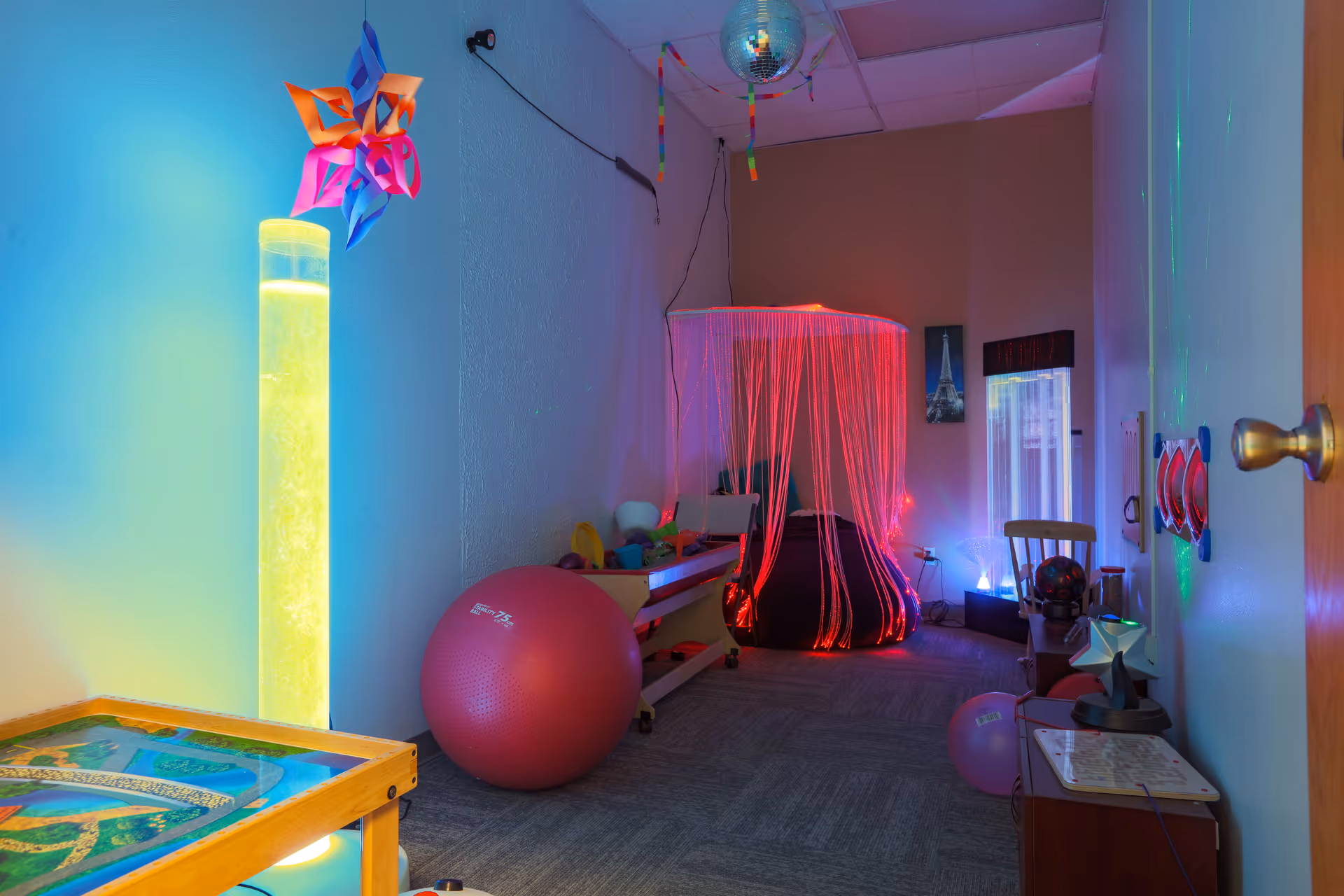 Colorful interior activity room with neon lights, string canopy, and exercise equipment.
