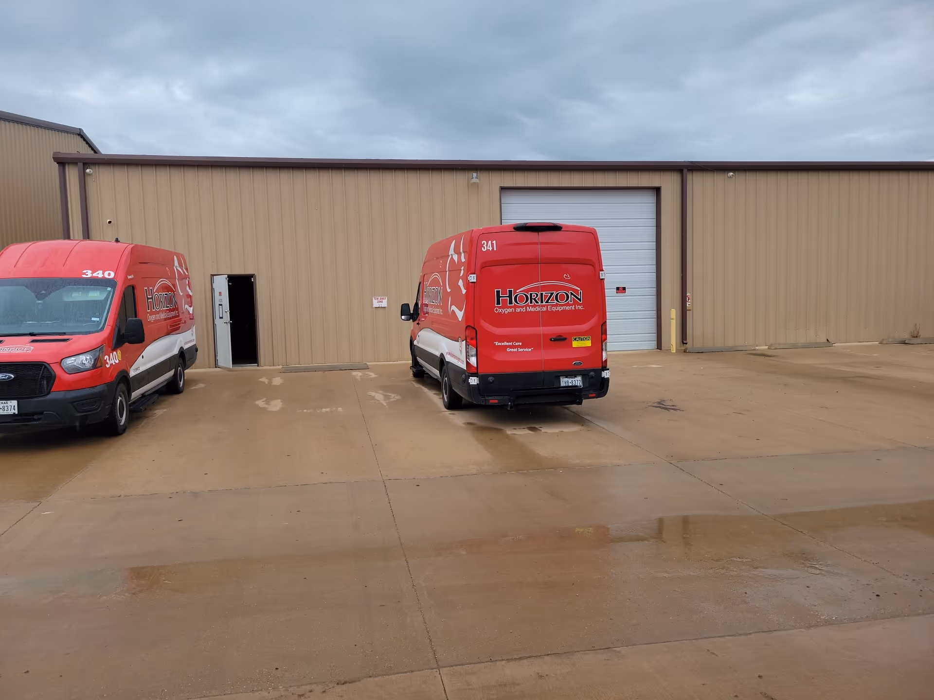 Red Horizon vans parked outside a beige industrial facility with a large garage door.