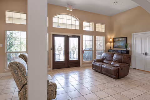 Senior living facility lobby with tiled floor, seating, and decorative glass doors.