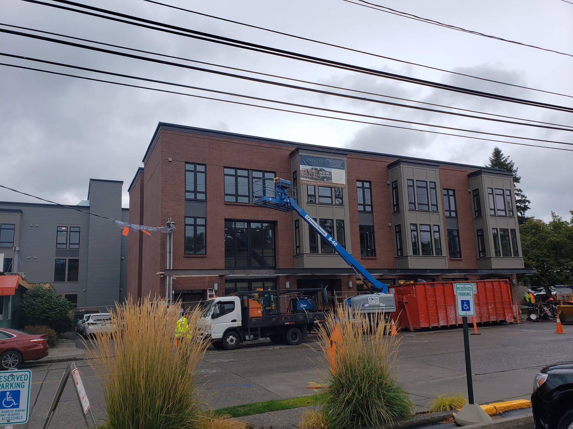 Exterior view of a brick senior living building under construction with a blue lift