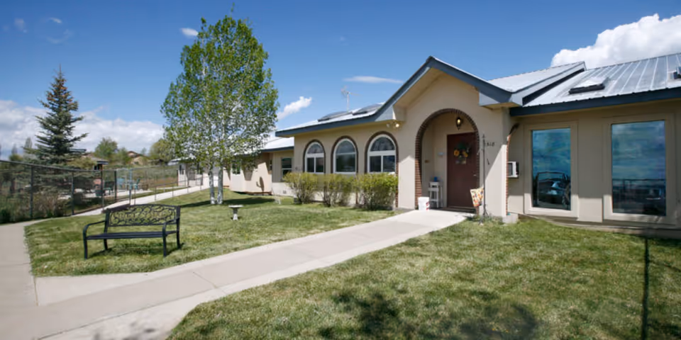 Exterior view of Sunshine Gardens Country Home with lawn, bench, and walkway.