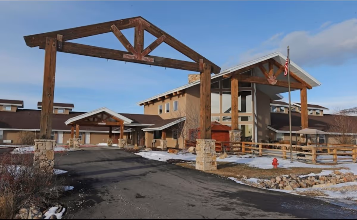 Exterior view of Elk Meadows Assisted Living & Memory Care entrance with a wooden arch.