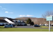 Exterior view of Holbrook Adult Home with parked cars and a blue sky.