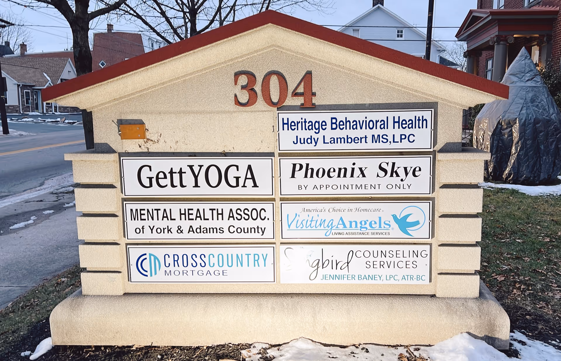 Outdoor signboard displaying multiple business signs including Visiting Angels.