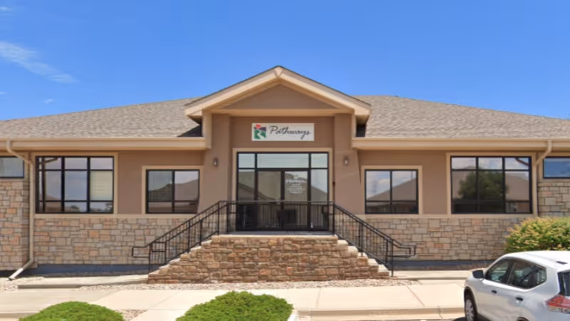 Front view of Pathways Hospice building with steps, railing, and a parked car.