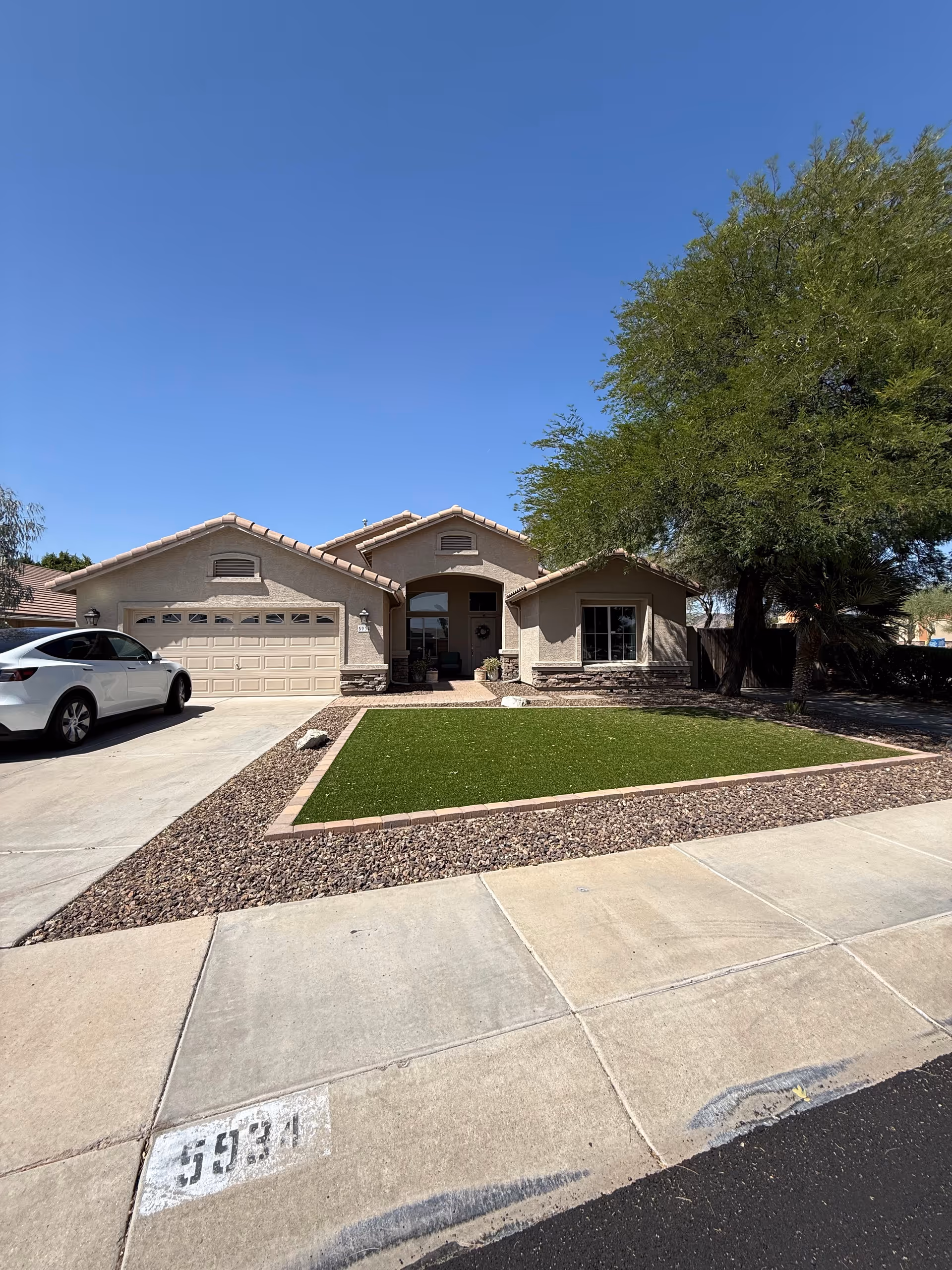 A single-story beige house with a two-car garage and a manicured front yard.