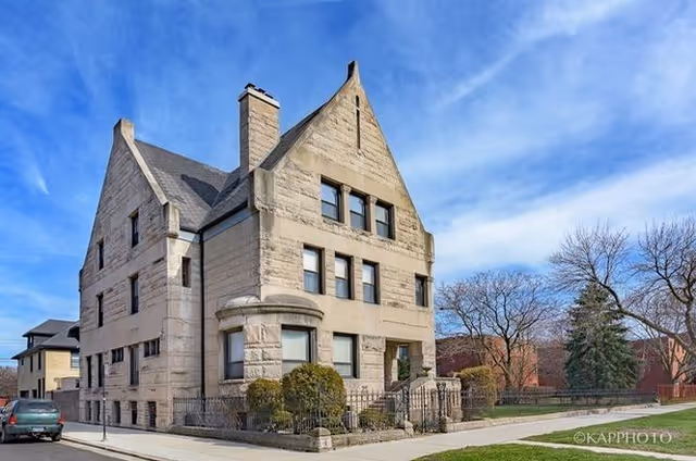 Stone, three-story senior living building with gabled roof and manicured front yard.