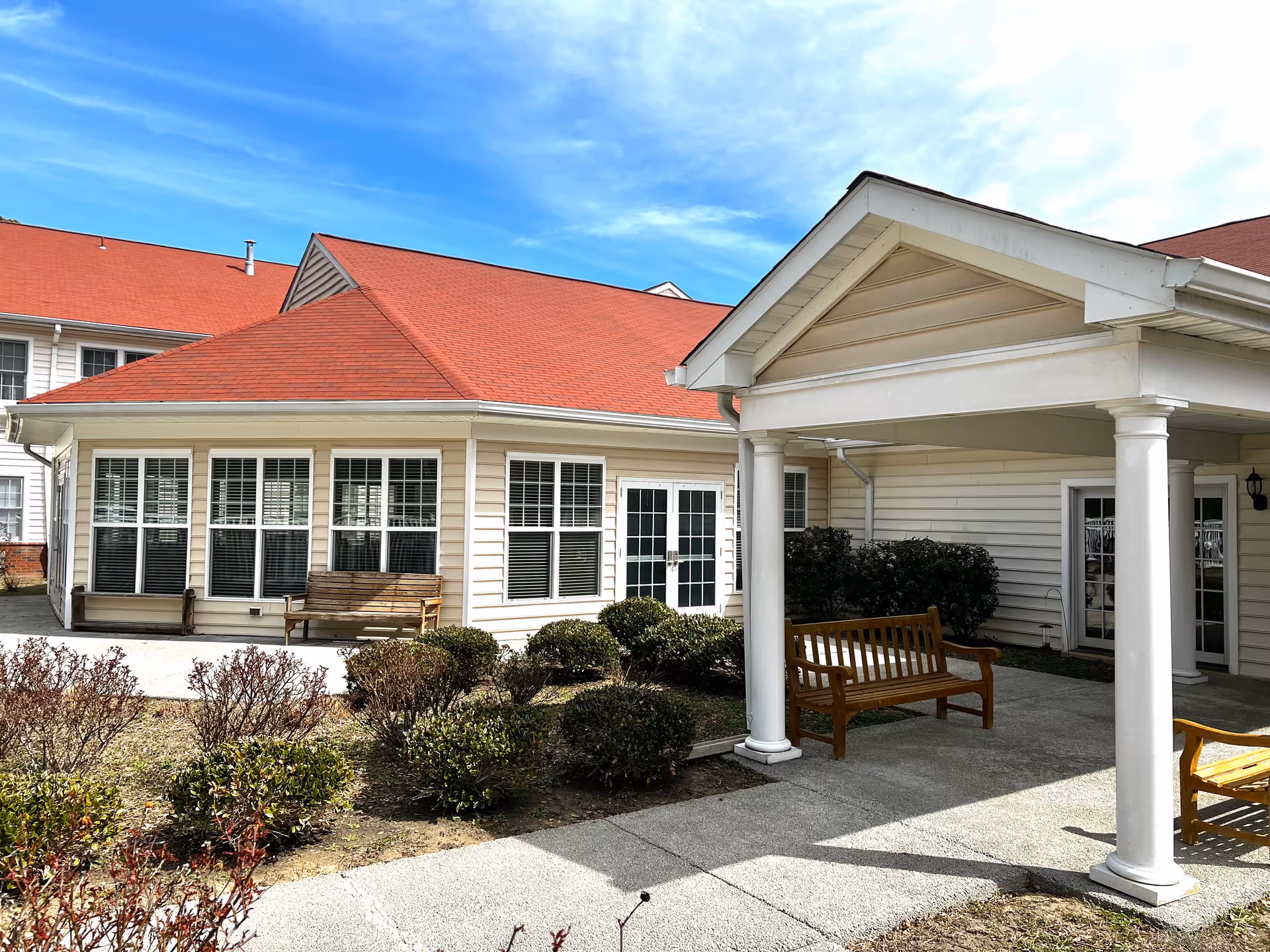 Exterior view of Solomons Nursing Center with red roofs, white siding, and benches.