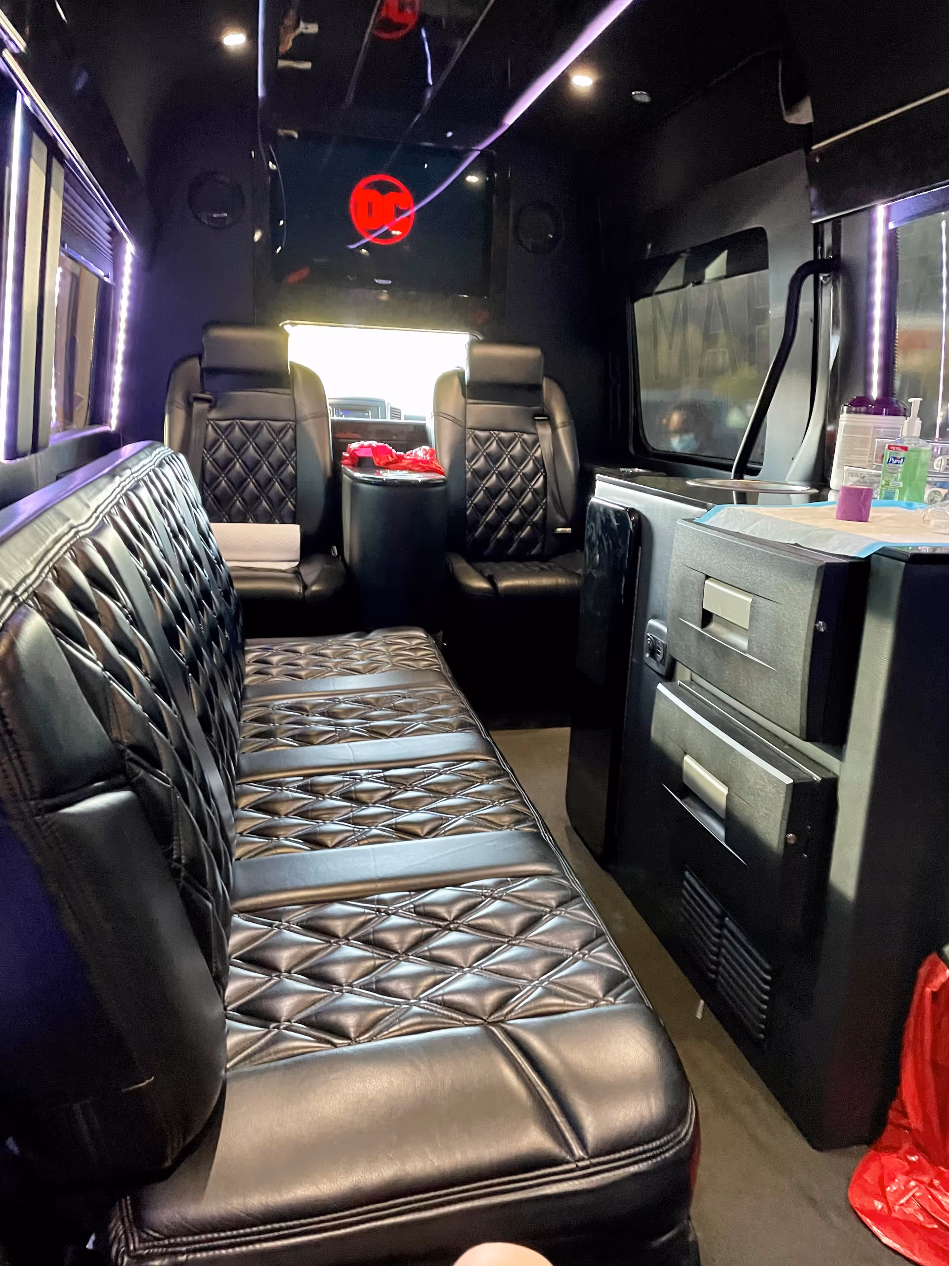 Luxurious black quilted leather seating inside a dark transport vehicle with purple lighting.