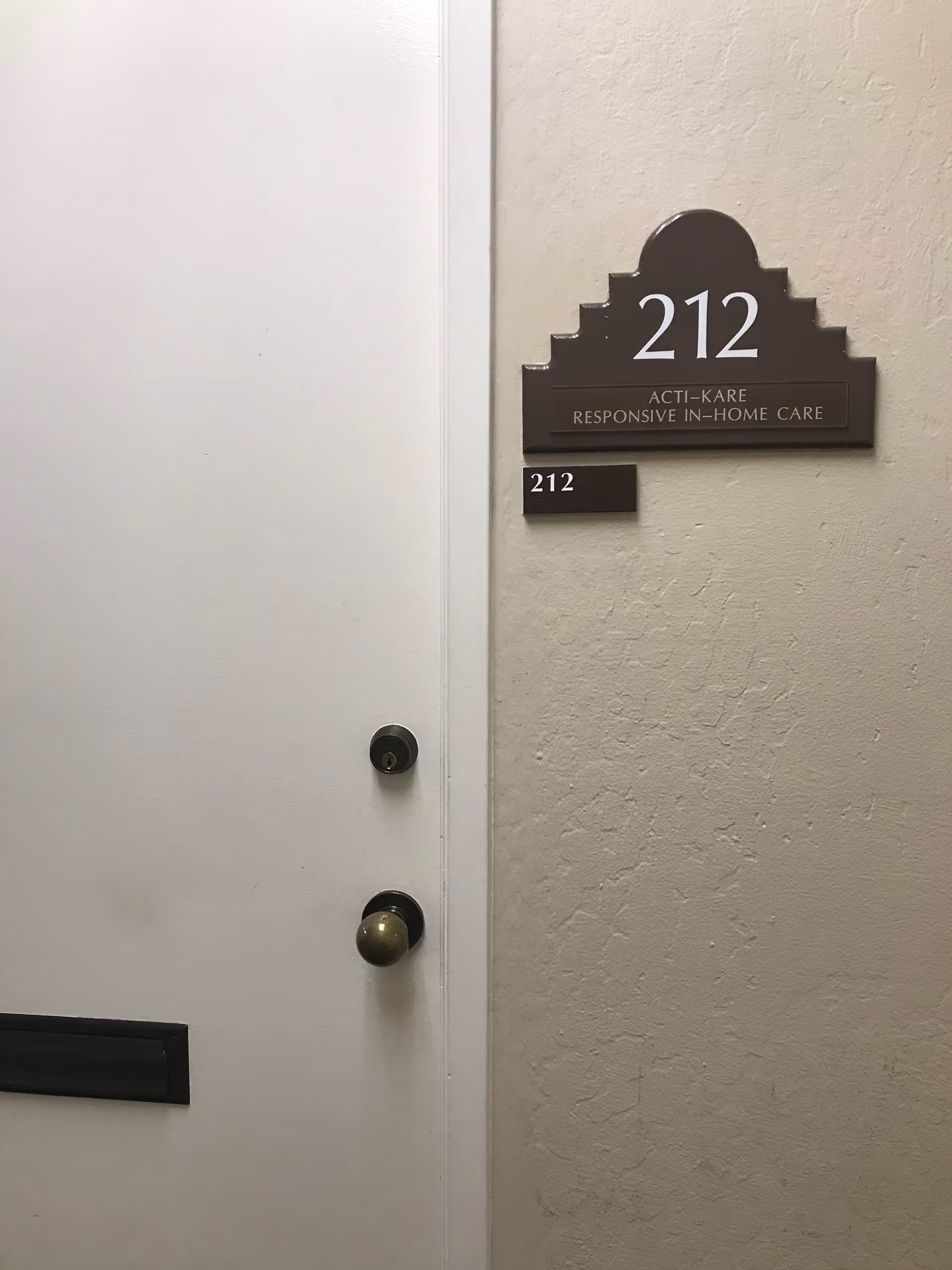 Interior hallway door with room 212 plaque for Acti-Kare Responsive In-Home Care.