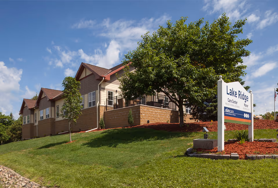 Exterior view of Lakeside Oasis facility with manicured lawn, trees, and a front sign.