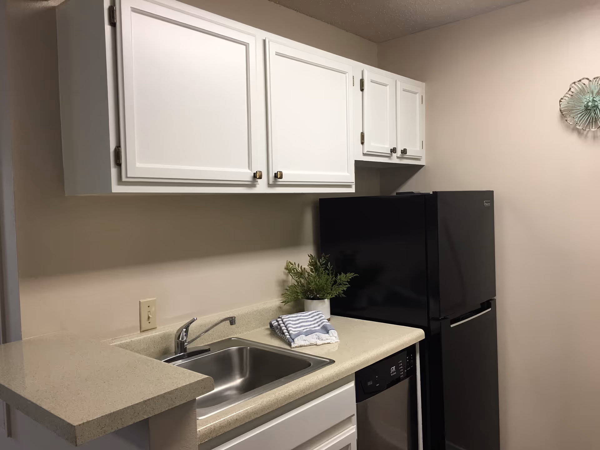 White cabinets, sink, and appliances in a compact senior living facility kitchen.