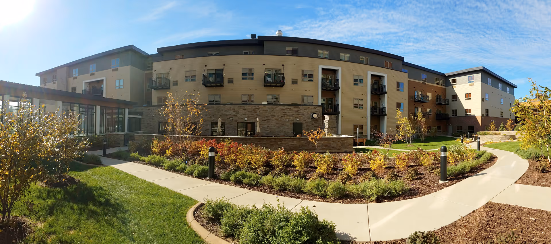 Exterior shot of Yorkshire of Edina Senior Living facility with landscaped walkway and balconies.
