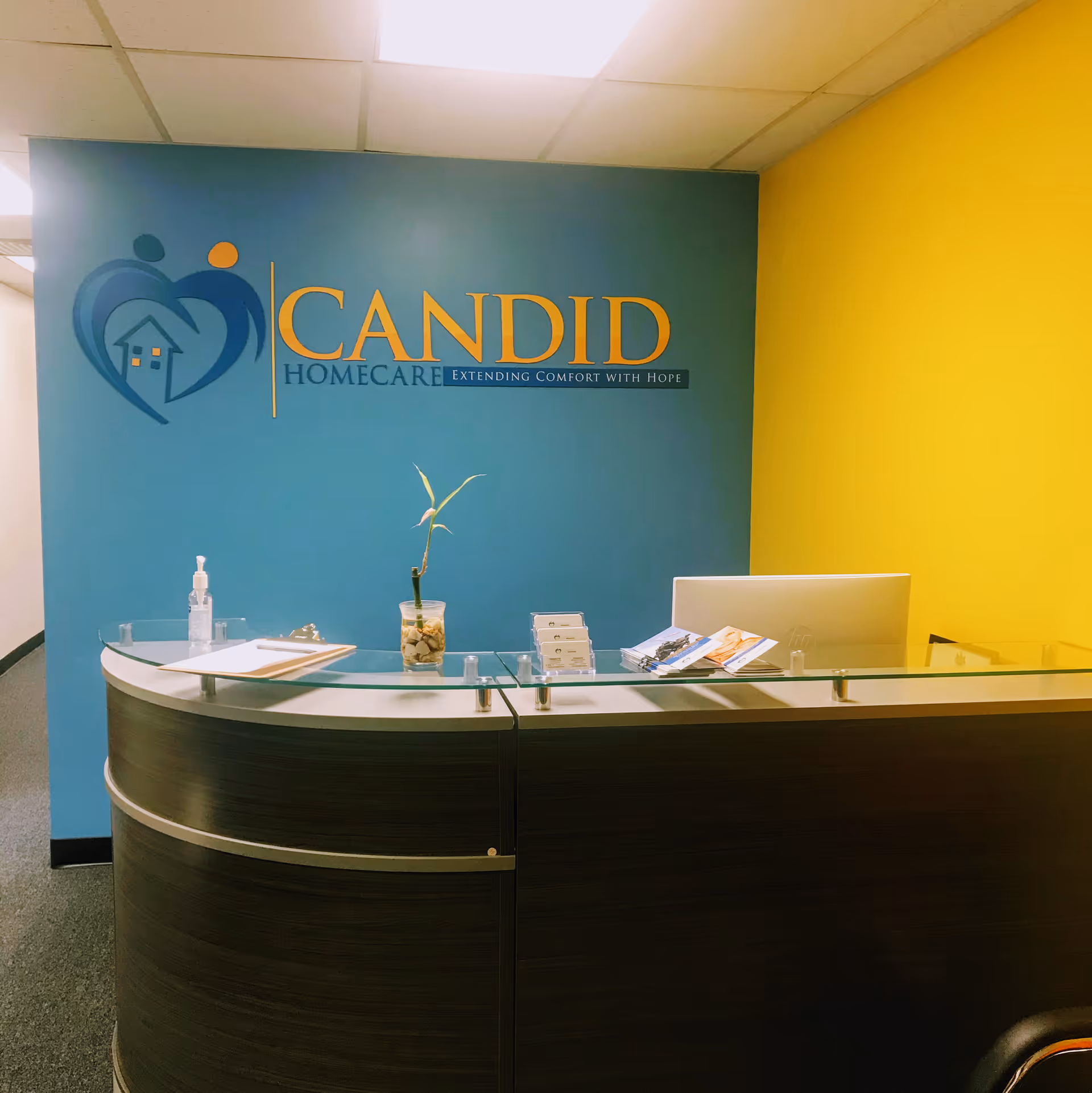 Reception desk in a colorful interior with CANDID HomeCare logo on blue wall.