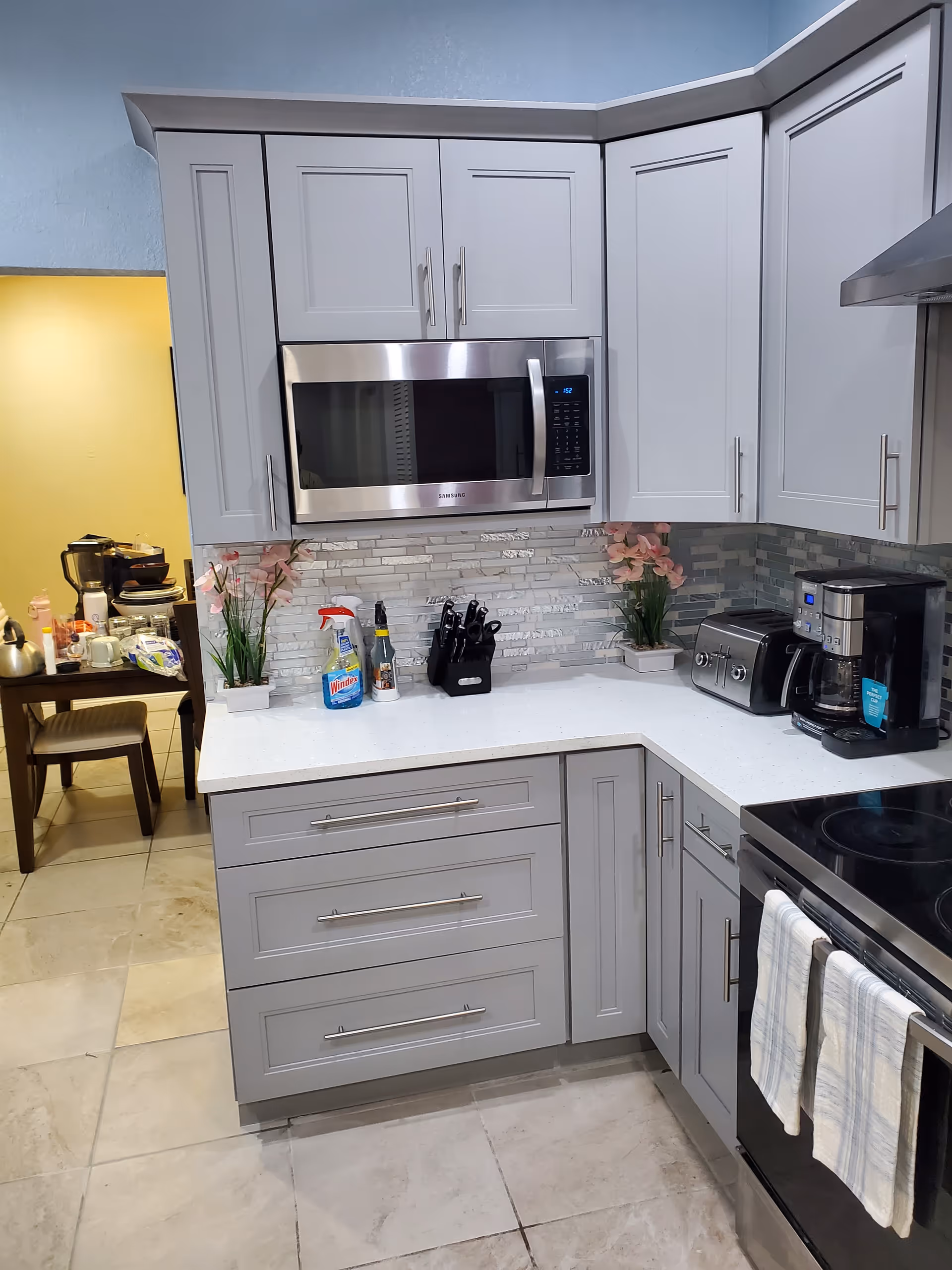 Modern gray kitchen in a senior living facility with upper cabinets and appliances.