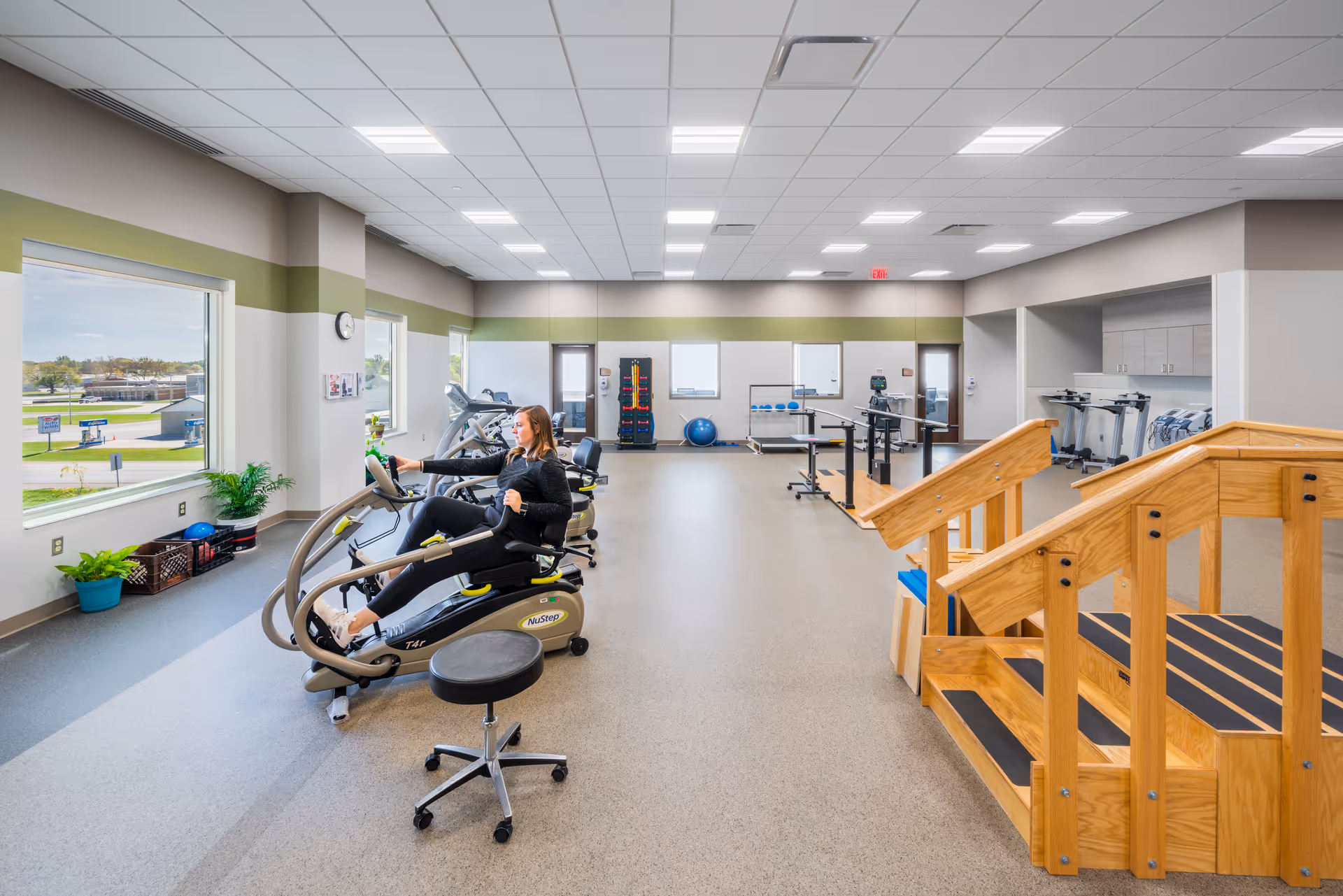 Bright Humboldt County Memorial Hospital physical therapy gym with cardio machines and wooden staircase.
