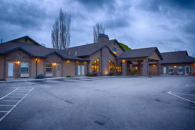 Exterior view of Pheasant View Assisted Living building with lit entrances and parking lot.
