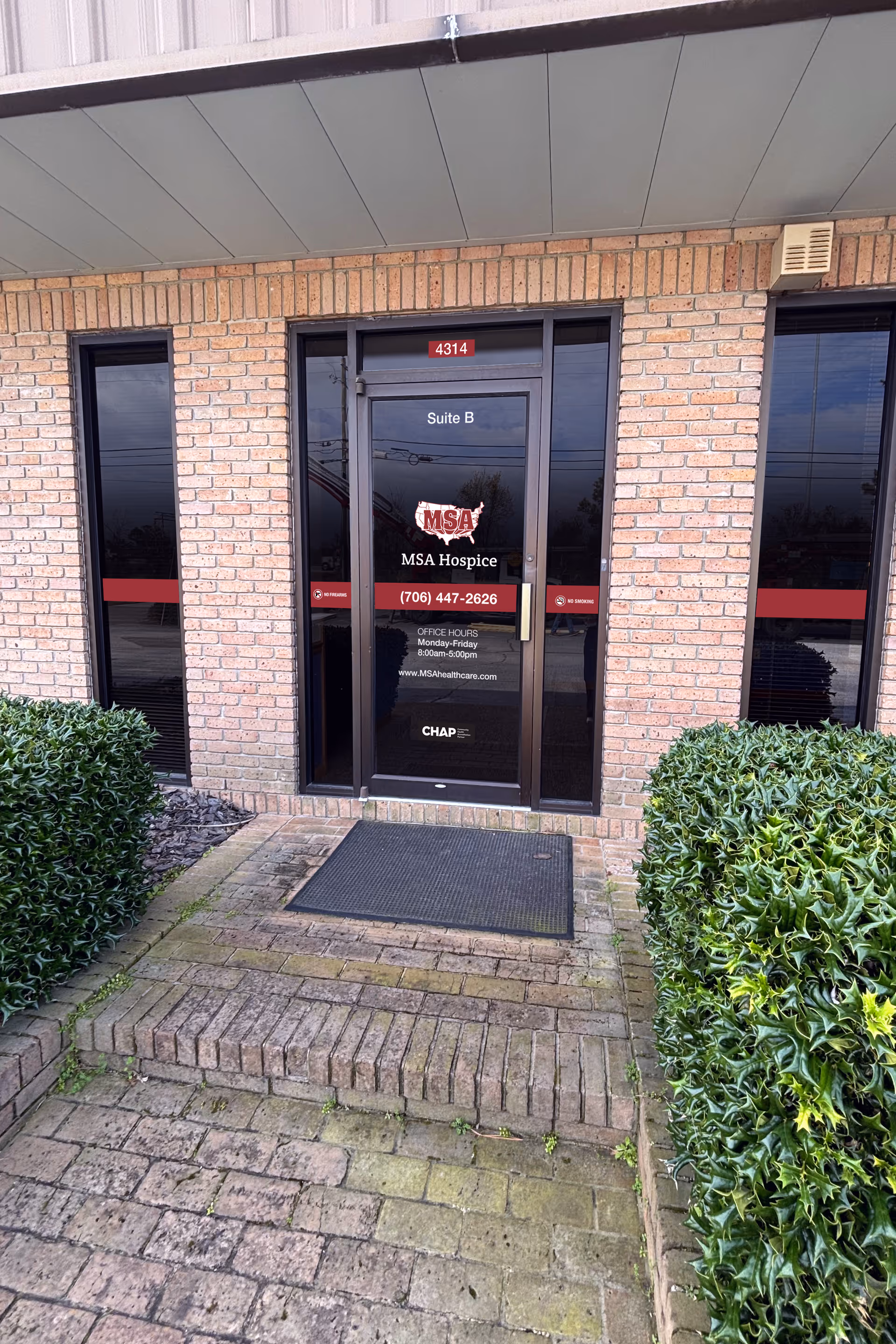Brick building entrance with glass door labeled MSA Hospice and Suite B