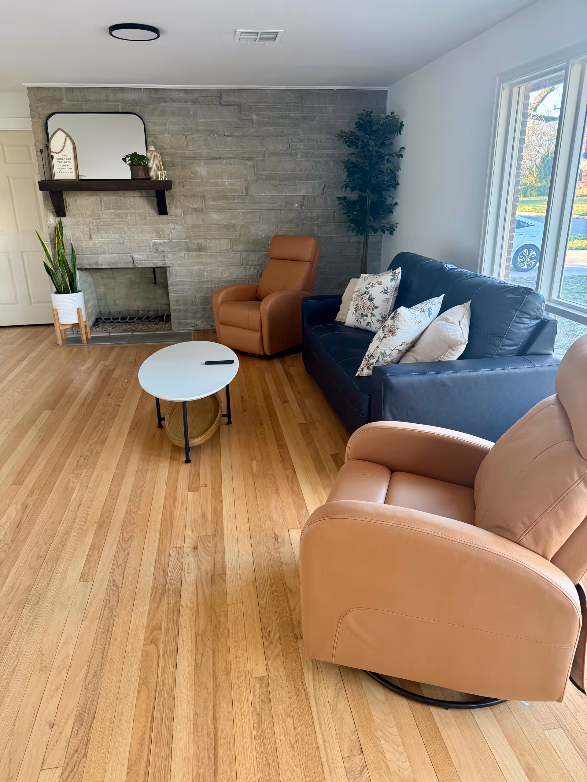 Cozy living room in Graceful Living Home Plus with recliners, sofa, table, fireplace, and plants.