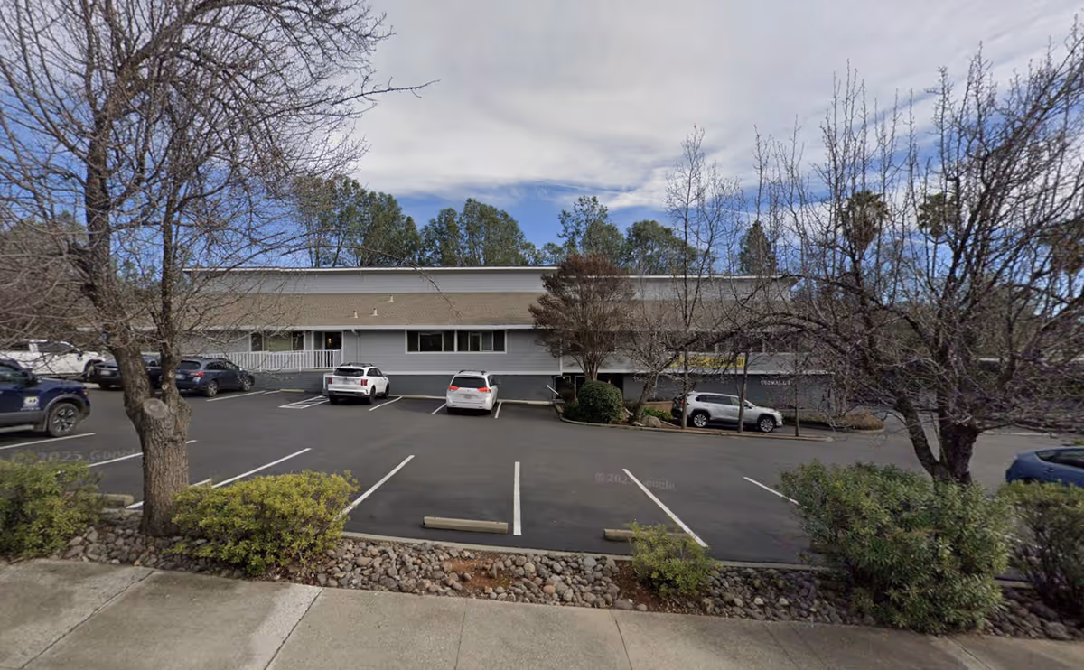 Front view of a single-story hospice building with a paved parking lot and bare trees.