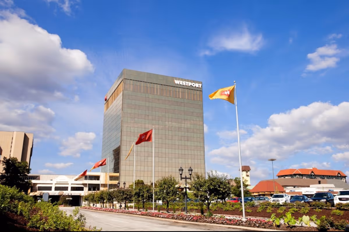Exterior view of a tall glass building with flagpoles and landscaping.