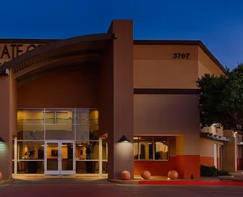 Front exterior of a senior living facility with glass doors and curved canopy.