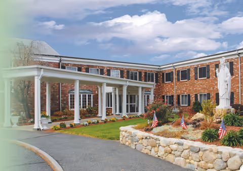 Brick exterior of senior living facility with a covered entrance and landscaped front garden.