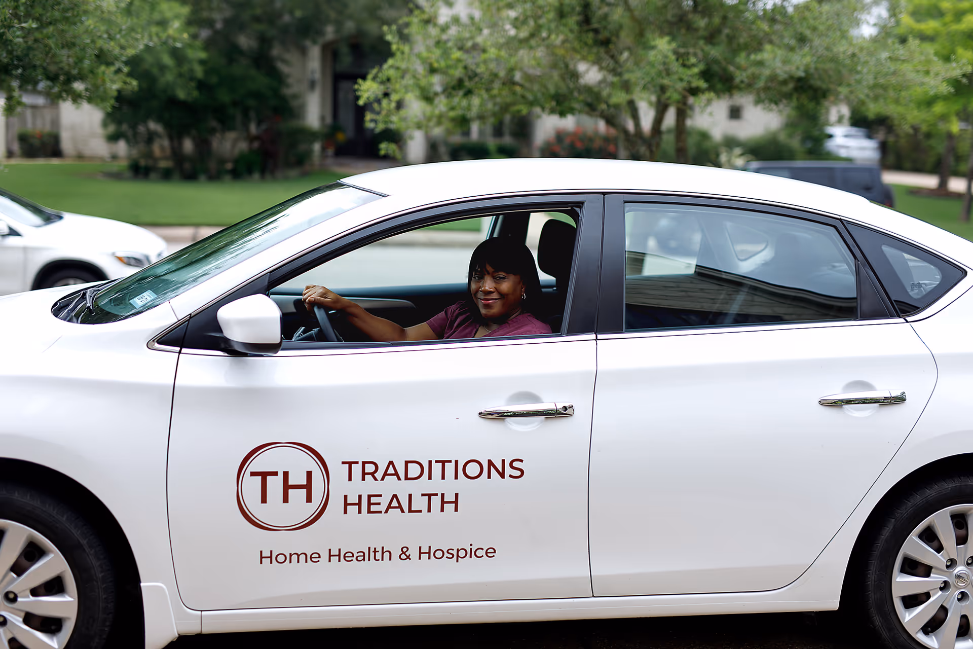 A driver sits in a white Traditions Health vehicle with logo visible.