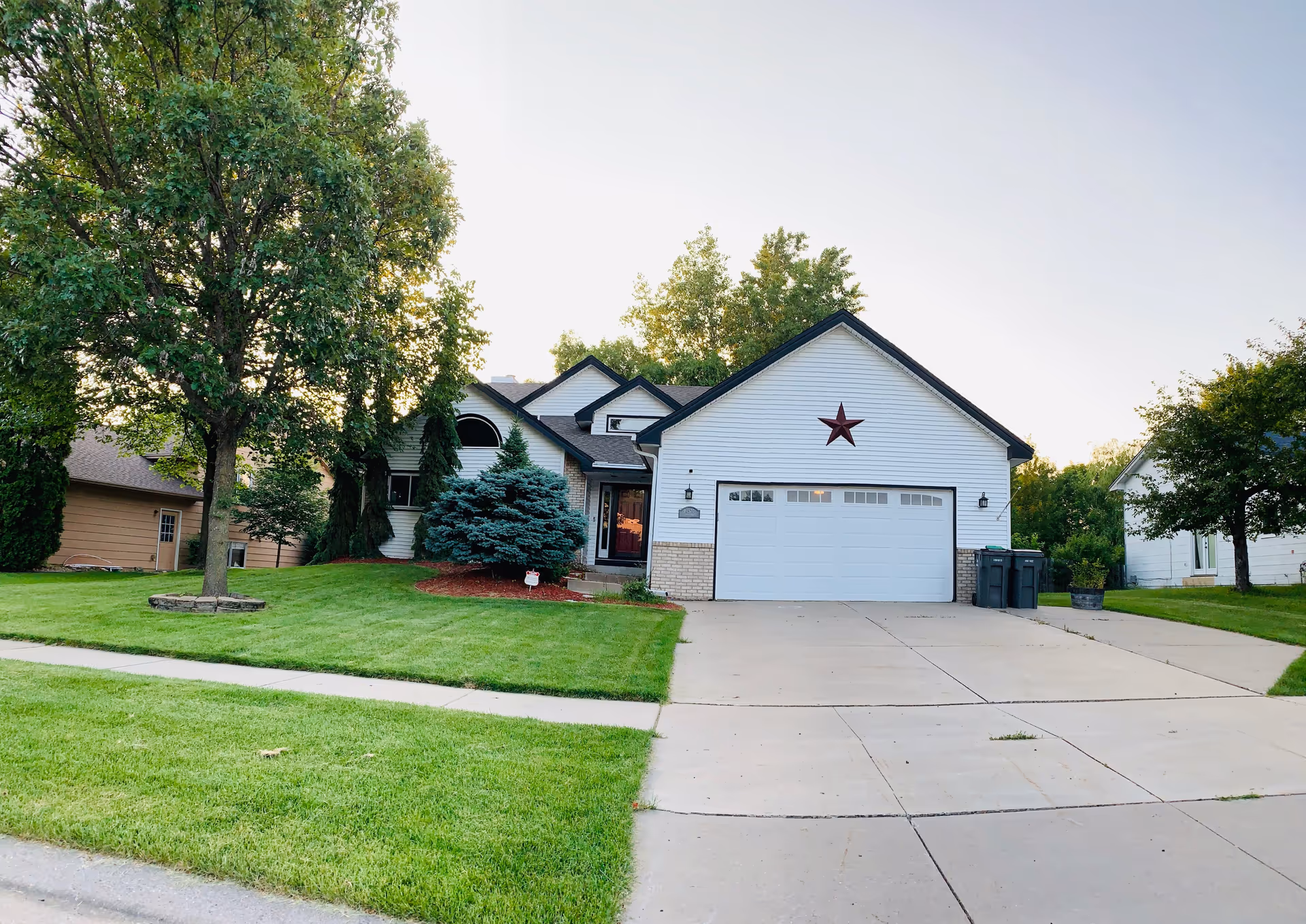 A suburban house with a two-car garage, manicured lawn, and driveway.