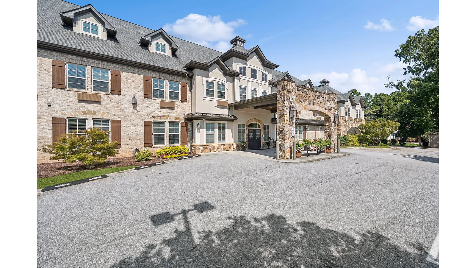 Senior living building with stone entrance canopy and parking lot.