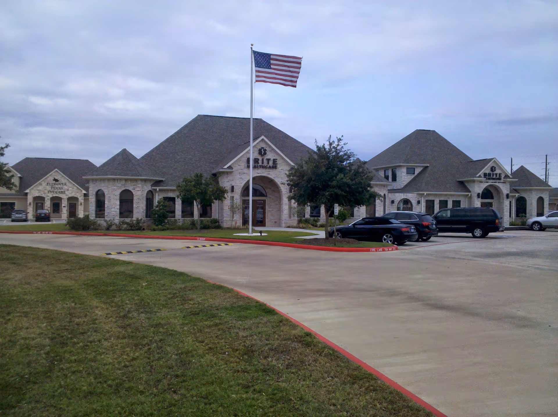 Exterior view of Brite Health Care facility with a waving American flag and parked cars.