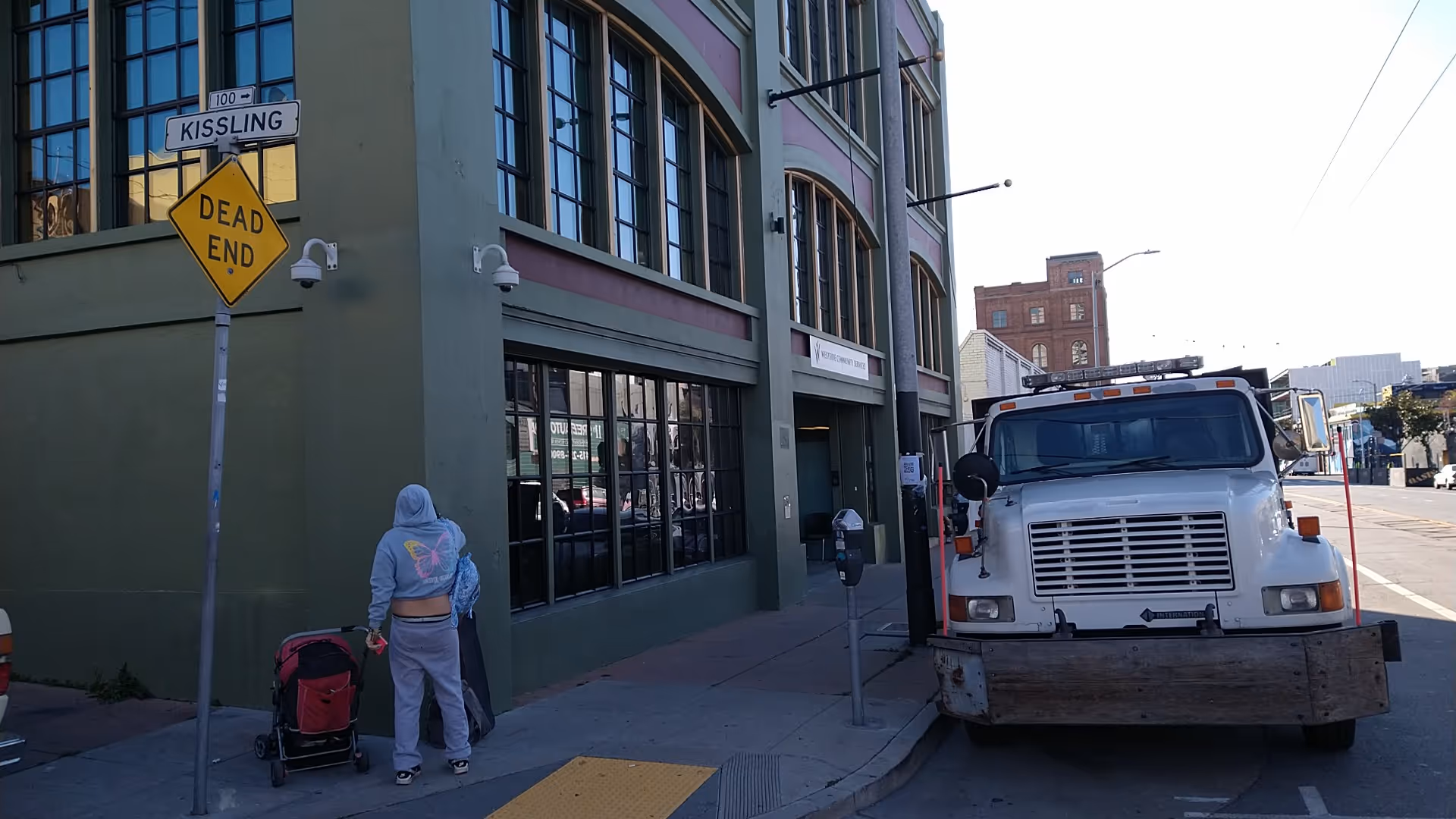 A storefront building on a city street with a large white truck parked nearby.